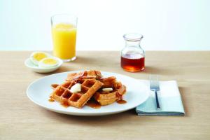 a plate of waffles with syrup and a glass of orange juice at Residence Inn by Marriott Houston NASA/Clear Lake in Friendswood