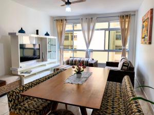 a living room with a table and chairs and a television at Beautiful condo by the shore in Santos