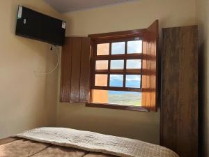 a bedroom with a window and a bed and a television at Pousada Paraíso in Lavras Novas