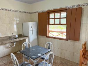 a small kitchen with a table and a refrigerator at Pousada Paraíso in Lavras Novas