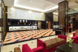 a lobby with a checkered floor and red chairs at Best Western Plus Makassar Beach in Makassar