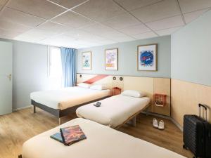 a hotel room with three beds and a window at ibis budget Angoulême Centre in Angoulême