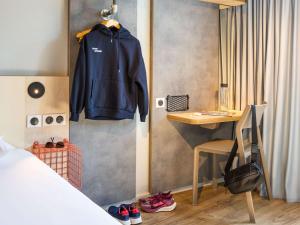 a bedroom with a blue jacket hanging on a wall at ibis budget Angoulême Centre in Angoulême