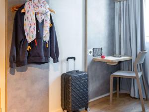 a room with a suitcase and a shirt and a chair at ibis budget Angoulême Centre in Angoulême