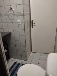 a bathroom with a white toilet and a door at Apartamento na praia dos sonhos in Itanhaém