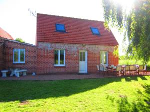 ein Backsteinhaus mit einem Tisch und Stühlen davor in der Unterkunft Gîte Marais Atypique in Clairmarais