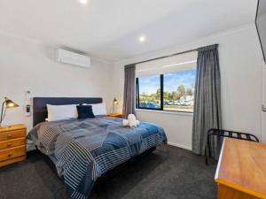 a bedroom with a bed and a large window at MiddleIsland-FREE & FAST wifi NETFLIX & aircon in Taupo