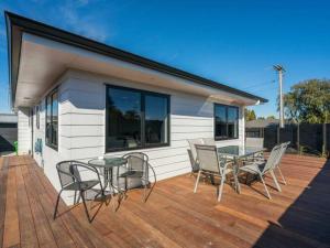 a house with a deck with a table and chairs at MiddleIsland-FREE & FAST wifi NETFLIX & aircon in Taupo