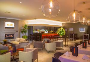 a restaurant with a bar with tables and chairs at Sudima Hotel Christchurch Airport in Christchurch