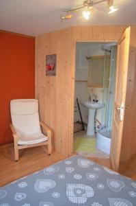 een badkamer met een stoel, een bad en een wastafel bij La Ferme du Vieux Sapin in La Bresse