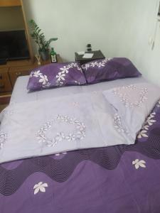 a bed with a purple comforter and pillows at Apartman Vuković in Foča