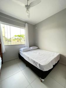 1 Schlafzimmer mit einem Bett mit einem Fenster und einer weißen Tagesdecke in der Unterkunft @casadepraiagrajau in Pontal do Paraná