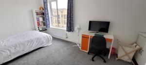 ein Schlafzimmer mit einem Bett und einem Schreibtisch mit einem Fernseher in der Unterkunft Stretford Townhouse Bedroom in Manchester