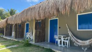 a house with a thatched roof and a table and chairs at Milagres Retrô- Studio in São Miguel dos Milagres