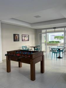 Una mesa de billar en una habitación con mesas y sillas. en Cobertura Santorini Nova com Spa e Solário na Praia Grande, en Ubatuba