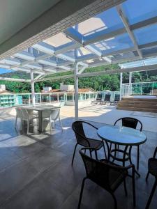 un patio con mesas y sillas bajo un techo en Cobertura Santorini Nova com Spa e Solário na Praia Grande, en Ubatuba 51 fotos más