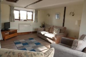 a living room with two couches and a tv at Bakers Mill Holiday Cottages in Beaminster
