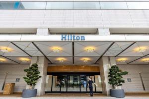 Un uomo in piedi di fronte a un edificio di Hilton Nagoya Hotel a Nagoya