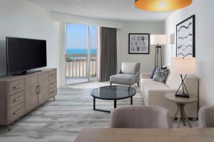 默特尔比奇Embassy Suites by Hilton Myrtle Beach Oceanfront Resort的客厅配有电视、沙发和椅子