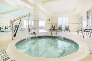 a jacuzzi tub in a large room with chairs at Hilton Garden Inn Roanoke Rapids in Roanoke Rapids