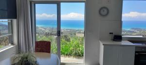 a kitchen with a large window with a view of the ocean at ON TOP Of THE WORLD Garden Studio in Kororo Basin