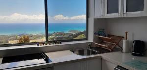 a kitchen with a sink and a large window at ON TOP Of THE WORLD Garden Studio in Kororo Basin