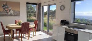 a kitchen with a table and chairs and a kitchen with windows at ON TOP Of THE WORLD Garden Studio in Kororo Basin +21 photos