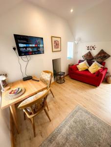 a living room with a red couch and a table at Loft cottage in Bonsall