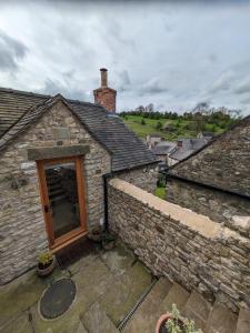 an old stone house with a window and a brick wall at Loft cottage in Bonsall