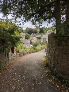 a road in a village with a stone wall at Loft cottage in Bonsall +8 photos