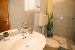 een badkamer met een witte wastafel en een toilet bij Apartments Petri in Tisno +37 foto's