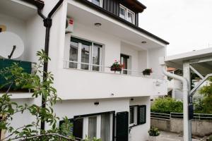 een wit gebouw met potplanten op het balkon bij Apartments Petri in Tisno