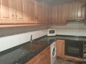a kitchen with wooden cabinets and a sink and a microwave at Alfred,s home in Valdeavellano de Tera