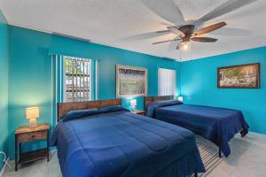 una camera blu con 2 letti e un ventilatore a soffitto di Home with pool and canal access to ocean a Port Charlotte