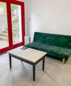 a living room with a green couch and a coffee table at Maison Atypique accès direct Paris, Cuisine design in Bois-Colombes