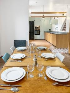 a wooden table with plates and wine glasses on it at Maison Atypique accès direct Paris, Cuisine design in Bois-Colombes