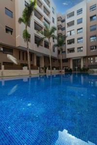 a large swimming pool with palm trees in front of a building at Luxury Duplex 3 Suites -Front Pool-Direct Pool Access in Marrakesh
