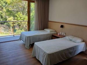 una camera d'albergo con due letti e una finestra di Casa do Castelo - Praia do Forte a Mata de Sao Joao Altre 37 foto