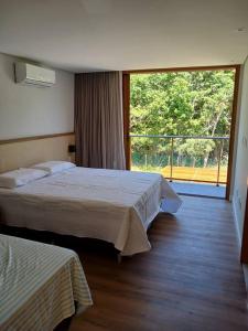 una camera d'albergo con due letti e una grande finestra di Casa do Castelo - Praia do Forte a Mata de Sao Joao