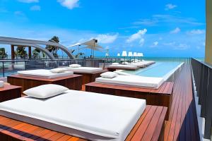 a row of beds on a balcony with a swimming pool at Setai Yacht com Café by Apartamentos Jampa in João Pessoa