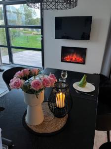 a table with a vase of flowers and a fire place at Enkhuizer Strand Chalet Hafenplätzchen mit Zaun Haus Nr 244 in Enkhuizen +2 photos
