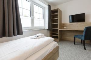 a room with a bed and a tv and a chair at Cuxlandhotel Studio 124 in Dorum Neufeld