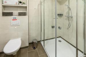 a bathroom with a toilet and a glass shower at Oase am Siel 4 in Dornumersiel