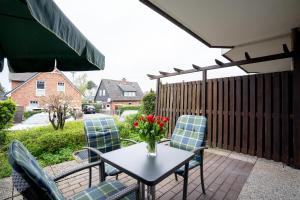 a table with chairs and a vase of flowers on a patio at DKK5 Ferienwohnung Ostseeperle in Niendorf