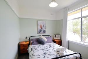 a bedroom with a bed and a window at Cosy Sun-Filled Cottage in Tenterfield