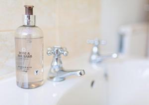 a bottle of soap sitting on a bathroom sink at Central 2 Bed House w/ Garden and Free Parking! in Cheltenham +44 photos
