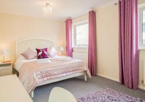 a bedroom with a bed with pink curtains and a window at Central 2 Bed House w/ Garden and Free Parking! in Cheltenham