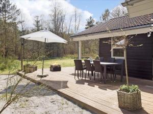 eine Holzterrasse mit Tisch und Sonnenschirm in der Unterkunft Tranquil Haven in Lyngsa - By Traum Ferienwohnungen in Sæby