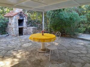 a yellow table and chairs on a patio with a fireplace at Apartments by the sea Mudri Dolac, Hvar - 4042 in Vrbanj