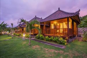 a house with a large deck in the yard at Lembongan Mantra Huts in Nusa Lembongan